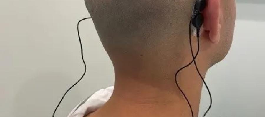 A person wearing a device that record EEG with behind-the-ear electrodes.