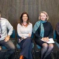 Four professionals sitting and smiling at the camera.
