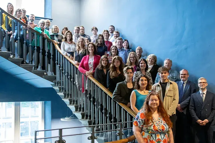 A large group of students and staff posing for a photo on the stairwell of the Edinburgh Futures Institute.
