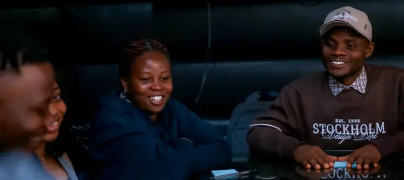 Four Mastercard Foundation scholars sitting and talking at a table.