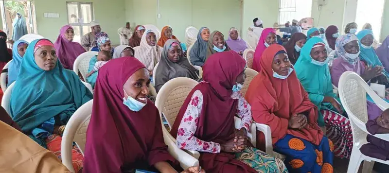 A large group of people sitting in rows in a community hall.