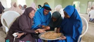 Four people sitting and eating Nigerian food.