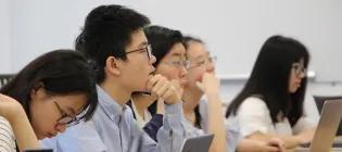 A group of students in a classroom with their laptops.