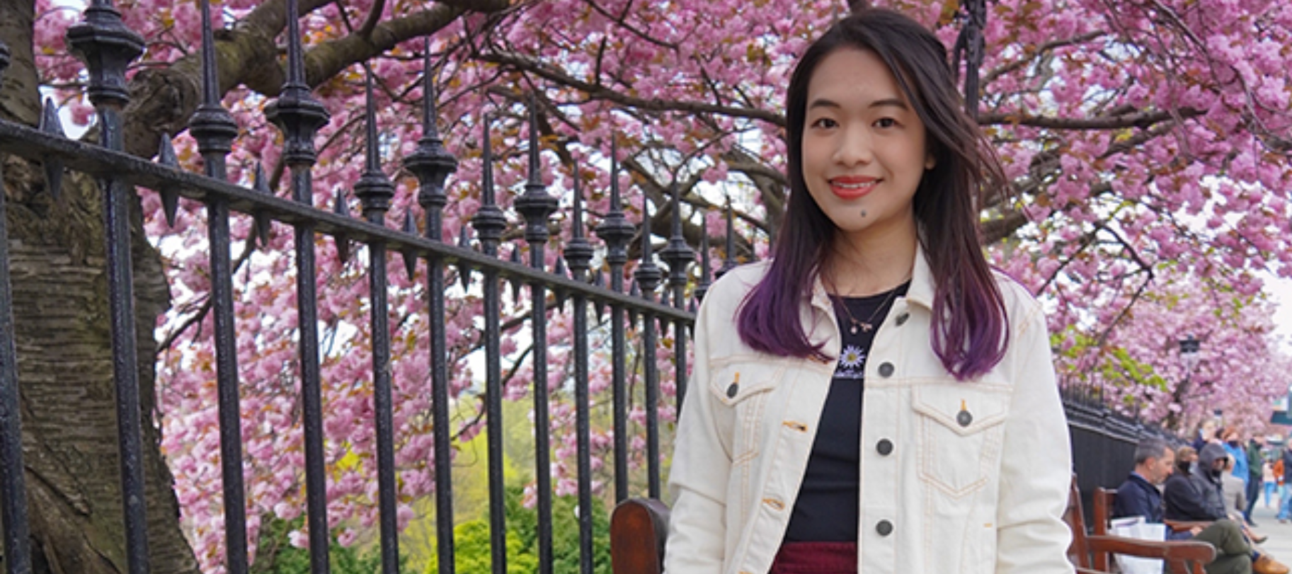 woman smiling in front of cherry blossom trees