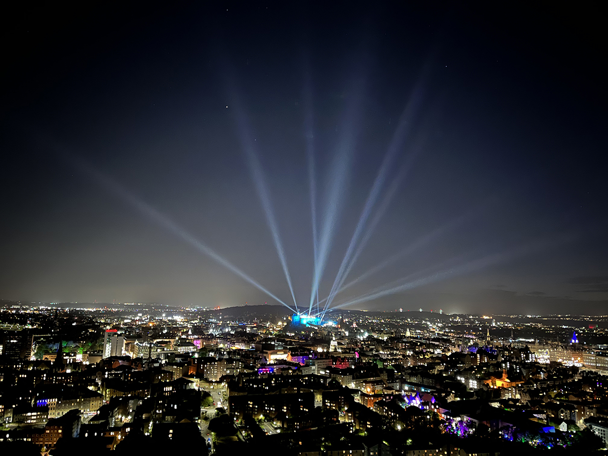 Beams of light shine upwards from Edinburgh Castle sitting in the city skyline