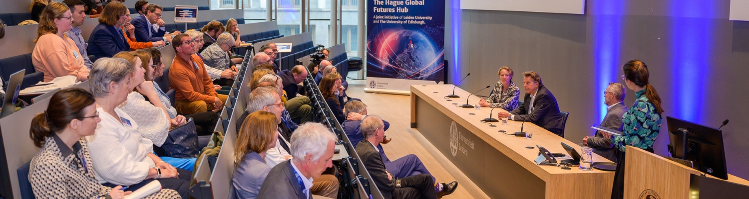 Staff and students listening to a panel speak at the launch event in The Hague