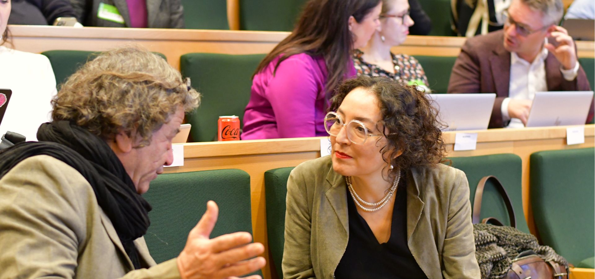 Colleagues speaking together in lecture hall