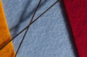 orange, blue and red fabric with brown thread crossing over in the middle